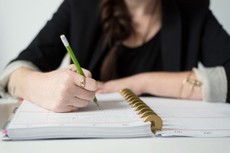Image of a woman writing in a planner